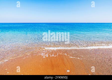 Le limpide acque turchesi del Mar Egeo si lavano delicatamente sulla spiaggia di sabbia dorata dell'isola di Rodi, Grecia. Foto Stock