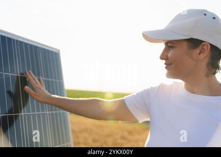 Una donna tocca un pannello solare al tramonto. Foto Stock