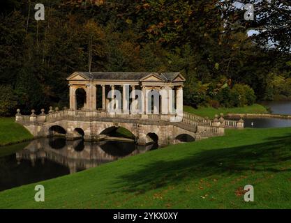 Il ponte palladiano, sotto il sole autunnale, sul lago nei giardini del Priory Park di Bath. Progettato nel XVIII secolo da Alexander Pope e landsca Foto Stock