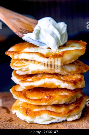 Pancake su un tavolo di legno con panna acida. Foto Stock