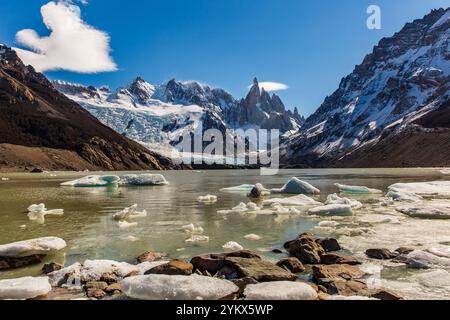 La splendida Laguna Torre si illumina sotto il sole, con montagne iconiche in lontananza e ghiaccio rotto che galleggia sulle sue acque tranquille Foto Stock