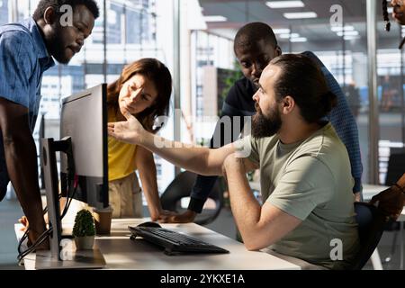 I dipendenti IT in ufficio discutono, fanno brainstorming, guardano i documenti aziendali online al computer. Team di dipendenti aziendali che discutono nello spazio di lavoro, svolgono attività, sono produttivi sul lavoro Foto Stock