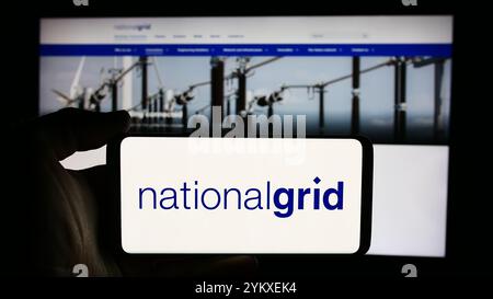 In questa illustrazione fotografica, una persona ha in mano un cellulare con il logo della società britannica National Grid plc davanti alla pagina Web aziendale. Foto Stock