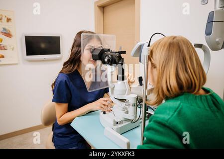 Optometrista che esegue un esame oculistico con apparecchiatura a fessura in una moderna clinica medica Foto Stock