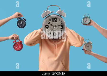 Uomo stressato con sveglia al posto della testa e delle mani con molti orologi su sfondo azzurro Foto Stock