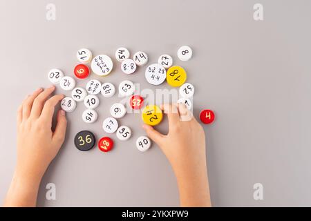 Impara le tabelle di moltiplicazione in modo interattivo per gli studenti di terza elementare, mano del bambino che tiene il tappo bianco della bottiglia con problemi matematici tra i numeri sparsi Foto Stock