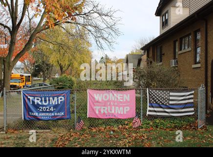 Trump 2024 riporta la bandiera America Back con una bandiera Women for Trump e una bandiera Thin Blue Line in autunno con uno scuolabus a Des Plaines, Illinois Foto Stock