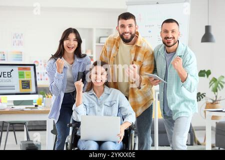 Designer soddisfatti con donna in sedia a rotelle in ufficio Foto Stock