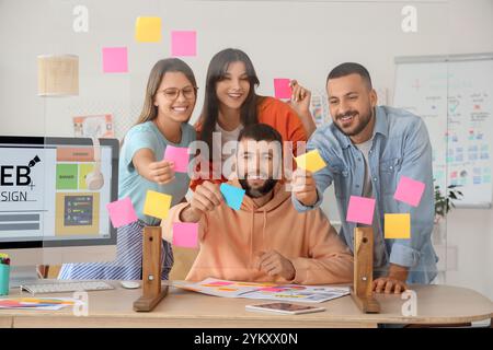Un team di designer che infila appunti di carta su vetro in ufficio Foto Stock