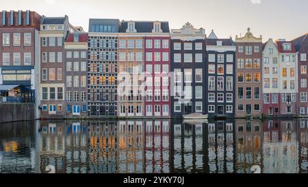 Mentre il sole tramonta su Amsterdam, gli affascinanti canali riflettono la splendida architettura degli edifici storici adornati con colori autunnali, creando un seren Foto Stock