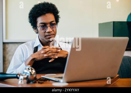 Nel moderno ufficio della torrefazione, un barista e un proprietario dell'azienda dedicati controllano la qualità dei chicchi su un notebook Foto Stock