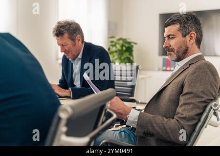 Dirigenti aziendali professionisti che esaminano i documenti durante riunioni strategiche in un ufficio moderno Foto Stock