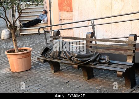 Roma, Italia - 31 ottobre 2024: Senzatetto Gesù la scultura in bronzo di Timothy Schmalz raffigurante Gesù come senzatetto, che dorme su una panchina del parco Foto Stock