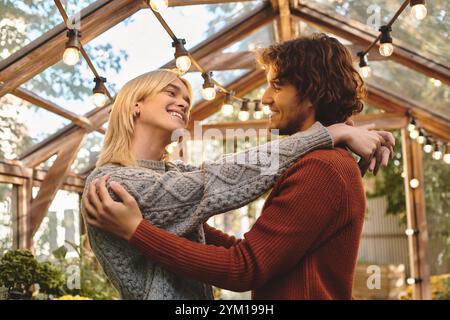 Giovani coppie gay che amano condividere un momento di gioia in una bellissima serra piena di vegetazione. Foto Stock