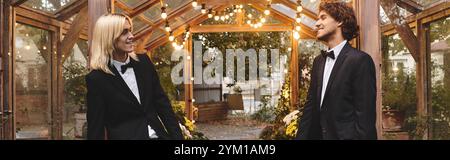 In una splendida serra adornata da luci calde, giovani coppie gay che amano condividere un momento di gioia, vestite elegantemente. Foto Stock