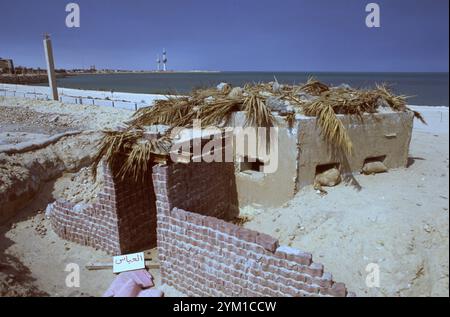 Prima guerra del Golfo: 11 marzo 1991 le iconiche torri del Kuwait si trovano sullo sfondo, oltre un bunker dell'esercito iracheno abbandonato sulla spiaggia di Ali Baba a Kuwait City. Aspettandosi che le forze della coalizione invadano dal mare, gli iracheni piazzarono delle difese a filo spinato e mezzi antisbarco lungo la spiaggia e nelle acque basse. Anche le spiagge erano minate. Foto Stock