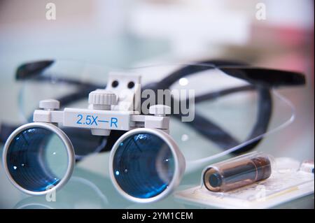 Primo piano di lenti dentarie o chirurgiche con lenti di ingrandimento su una superficie riflettente. Apparecchiature mediche professionali utilizzate per lavori di precisione. Foto Stock