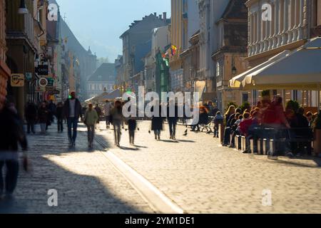 Brasov, Romania - 22 ottobre 2024: Vivace strada Republicii a Brasov: Scene illuminate dal sole del centro affollato della Romania. Foto Stock