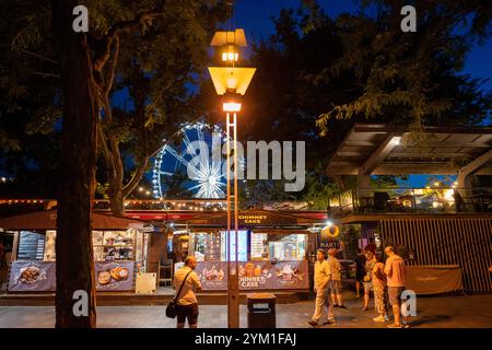 Budapest, Ungheria - 9 luglio 2024: Stallo della torta del camino e ruota panoramica: Una deliziosa scena in via Deák Ferenc. Foto Stock