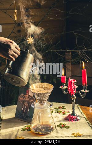 Metodo di estrazione alternativo per il caffè con filtro. La ragazza versa acqua calda sui chicchi di caffè tostati e macinati contenuti nel filtro di carta. Ceramica Foto Stock