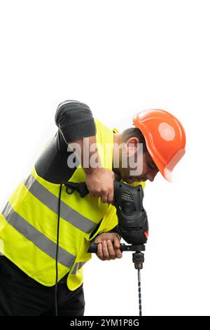 Uomo costruttore che indossa giubbotto di sicurezza e elmetto sul posto di lavoro per praticare fori utilizzando l'attrezzo elettrico sotto isolato su sfondo bianco studio Foto Stock