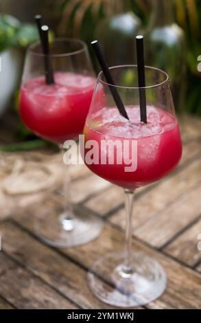 Cocktail rosso con ghiaccio in vetro con stelo su superficie di legno Foto Stock