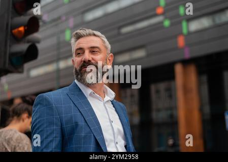 Un uomo d'affari bello e maturo che cammina per la strada della città. Foto Stock