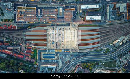 Vista aerea del grande parcheggio con auto a Cracovia, Polonia. Stazione ferroviaria con treni, treni da sotto Foto Stock