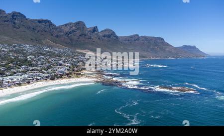 Eine beeindruckende Luftaufnahme des Strandes von Camps Bay a Kapstadt, Südafrika. DAS foto zeigt die malerische Küstenlinie mit türkisfarbenem Wasser, felsigen Klippen und einer Grünen Parklandschaft, eingerahmt von der urbanen Umgebung. Der klarblaue Himmel und die ruhigen Wellen unterstreichen die natürliche Schönheit der Region. Perfekt geeignet für Reiseberichte, Naturthemen oder die Darstellung südafrikanischer Landschaften. *** Un'impressionante vista aerea della spiaggia di Camps Bay a città del Capo, Sud Africa la foto mostra la pittoresca costa con acqua turchese, scogliere rocciose e un verde Foto Stock