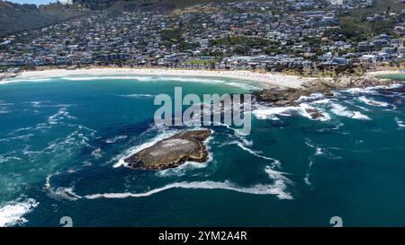 Eine beeindruckende Luftaufnahme des Strandes von Camps Bay a Kapstadt, Südafrika. DAS foto zeigt die malerische Küstenlinie mit türkisfarbenem Wasser, felsigen Klippen und einer Grünen Parklandschaft, eingerahmt von der urbanen Umgebung. Der klarblaue Himmel und die ruhigen Wellen unterstreichen die natürliche Schönheit der Region. Perfekt geeignet für Reiseberichte, Naturthemen oder die Darstellung südafrikanischer Landschaften. *** Un'impressionante vista aerea della spiaggia di Camps Bay a città del Capo, Sud Africa la foto mostra la pittoresca costa con acqua turchese, scogliere rocciose e un verde Foto Stock