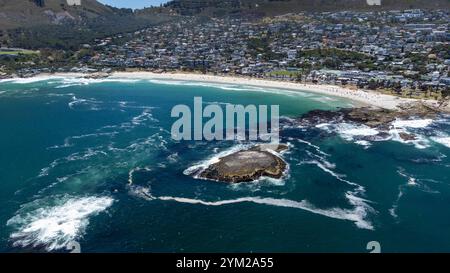 Eine beeindruckende Luftaufnahme des Strandes von Camps Bay a Kapstadt, Südafrika. DAS foto zeigt die malerische Küstenlinie mit türkisfarbenem Wasser, felsigen Klippen und einer Grünen Parklandschaft, eingerahmt von der urbanen Umgebung. Der klarblaue Himmel und die ruhigen Wellen unterstreichen die natürliche Schönheit der Region. Perfekt geeignet für Reiseberichte, Naturthemen oder die Darstellung südafrikanischer Landschaften. *** Un'impressionante vista aerea della spiaggia di Camps Bay a città del Capo, Sud Africa la foto mostra la pittoresca costa con acqua turchese, scogliere rocciose e un verde Foto Stock