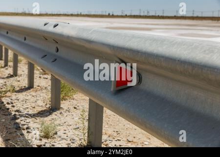 catarifrangenti stradali rossi lungo la strada. recinzione stradale metallica. Sicurezza stradale e stradale Foto Stock