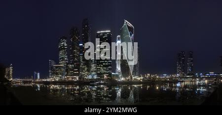 Mosca, Russia - 20 agosto 2024: Una splendida foto panoramica dei grattacieli della città di Mosca di notte, che si riflettono sul fiume Mosca, mostrando archi moderni Foto Stock