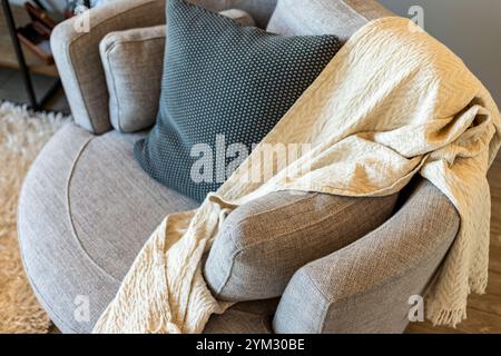 Una sedia con una coperta bianca sopra di essa e un cuscino nero su di essa. La coperta copre l'intera sedia e il cuscino è sul retro del ch Foto Stock