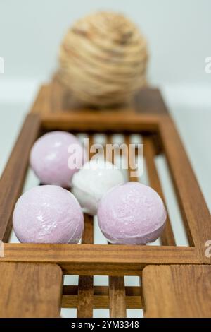 Un vassoio di legno con quattro bombe da bagno bianche e rosa. Le bombe da bagno sono disposte in fila e sono circondate da una corda. Le bombe da bagno potrebbero farlo Foto Stock