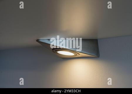 Una luce d'angolo è illuminata e luminosa su una parete. La luce si trova su una staffa metallica Foto Stock