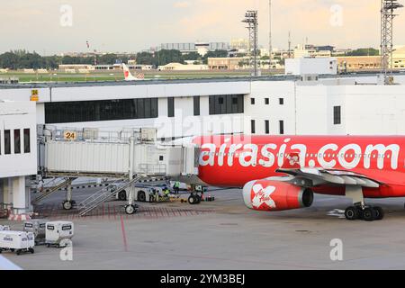 L'aereo rosso e bianco è parcheggiato al cancello passeggeri e collegato ad esso con un ponte jet. Foto Stock