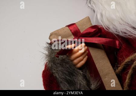 Primo piano della mano di Babbo Natale che regge un grande regalo di natale con il nastro rosso. Concetto di beneficenza, donazione e donazione di regali. Foto Stock