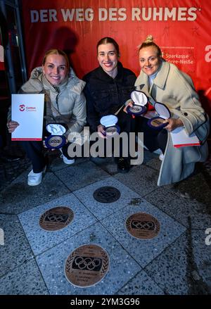 20 novembre 2024, Brandeburgo, Cottbus: I ciclisti Emma Hinze (l-r), Pauline Grabosch e Lea Sophie Friedrich siedono di fronte al municipio di Cottbus mentre ricevono le loro nuove targhe per "la strada della gloria". Gli atleti hanno vinto tutte le medaglie ai Giochi Olimpici di Parigi del 2024. Queste targhe sono state aggiunte a "The Road to Glory" durante un tributo pubblico. Oltre a vincere una medaglia ai Giochi olimpici, l'appartenenza a un club sportivo Cottbus o la nascita a Cottbus è un prerequisito per l'inclusione in "The Path to Glory". Ad oggi, sono stati premiati 76 vincitori delle medaglie olimpiche e paralimpiche Foto Stock