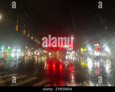 I semafori si vedevano attraverso il parabrezza piovoso a tarda notte in una città Foto Stock