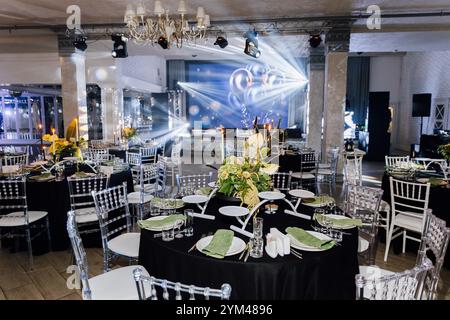 Elegante sala per banchetti con centrotavola floreale, tavoli e illuminazione scenica per eventi Foto Stock