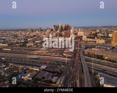 Vista aerea dello skyline del centro di Los Angeles al crepuscolo, che mostra il traffico dell'ora di punta sulle autostrade, l'espansione urbana circostante e il cielo del tramonto Foto Stock