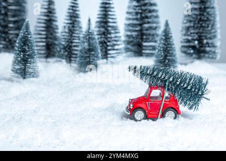 Macchinina rossa in una foresta invernale con un albero di Natale sul tetto. Natale e Capodanno. Foto Stock