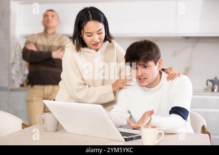 La ragazza convince un giovane a smettere di giocare ai videogame. Padre turbato in sottofondo Foto Stock