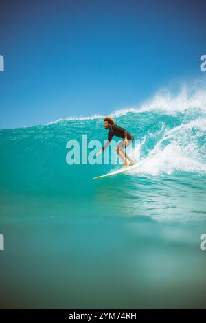 Un surfista sta cavalcando un'onda nell'oceano. Il surfista indossa una muta nera. L'oceano è calmo Foto Stock