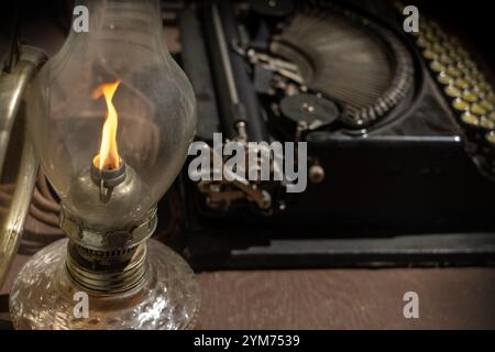 Una lampada a olio è accesa su un tavolo con una macchina da scrivere vintage Foto Stock