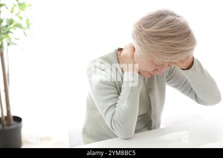Donna di mezza età che sente dolore dietro al collo Foto Stock