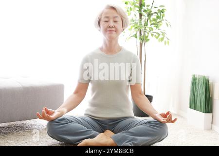 Donna anziana con postura yoga di base Foto Stock