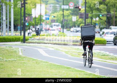 Giovane donna che consegna pacchi in bicicletta Foto Stock