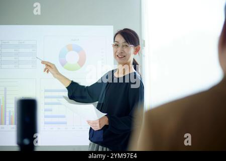 Donna giapponese anziana che fa una presentazione in ufficio Foto Stock